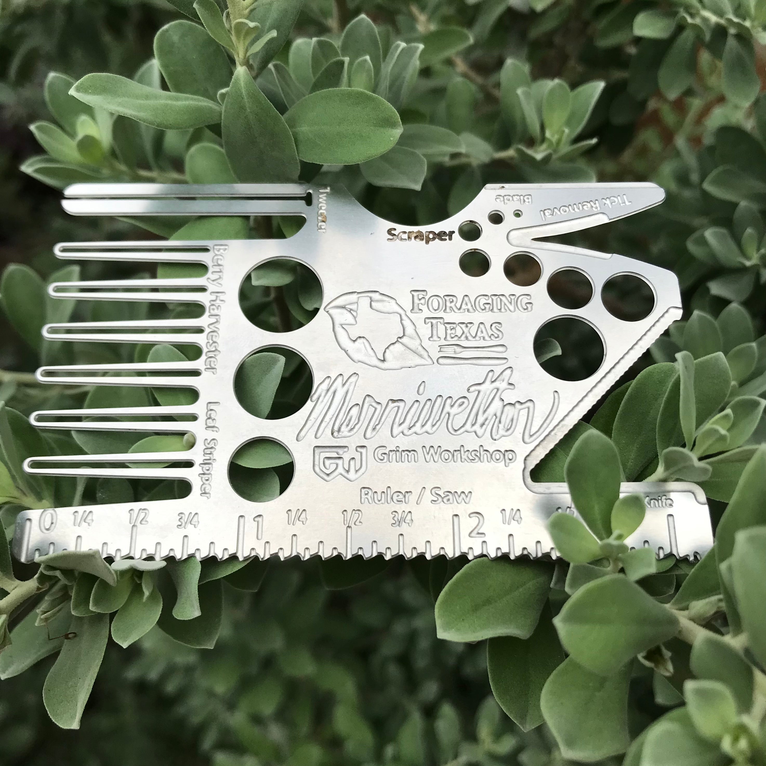 Flat metal card with leaf and bark strippers, tweezers, mushroom harvesting knife, wood tick remover, saw, ruler, and berry comb, designed for carrying in wallet, ready to forage at any time